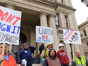 Union workers hold up a signs during a rally outside the Capitol in Lansing, Mich., on Dec. 6, 2012, as Senate Republicans introduced right-to-work legislation in the waning days of the legislative session. (AP Photo/Carlos Osorio)