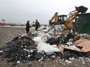 Tow truck operators prepare to remove recycled material that fell onto the road Tuesday, Dec. 4, 2012, at the new roundabout at highway 3 near Howard Ave. in Windsor, Ont. The mishap occurred at approximately 8:30 a.m. A Turtle Island truck lost its load while going through the roundabout. No one was injured. (DAN JANISSE/The Windsor Star)