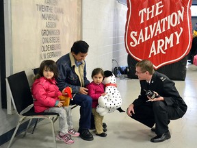Perron Goodyear,  right, Salvation Army public relations and development representative, presents a toy to a family during the Salvation Army Toy Drive in Windsor on December 5, 2012. (Windsor Star files)