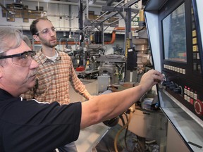 St. Clair College instructor Gary Steed (L) teaches apprentice Ryan Solcz techniques on a vertical mill machine. (DAN JANISSE/The Windsor Star)
