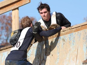 Derrick Brecka helps a competitor up a wall during the World's Toughest Mudder. (Courtesy of Derrick Brecka)