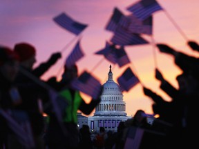 In this file photo, people wave American flags as people gathered near the U.S. Capitol building on the National Mall for the Inauguration ceremony on January 21, 2013 in Washington, DC.  U.S. President Barack Obama was ceremonially sworn in for his second term.  (Photo by Joe Raedle/Getty Images)