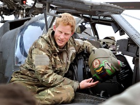 Prince Harry, shows a television crew his flight helmet as he makes early morning checks as he sits on an Apache helicopter at the British controlled flight-line at Camp Bastion on December 12, 2012 in Afghanistan. Prince Harry has served as an Apache Helicopter Pilot/Gunner with 662 Sqd Army Air Corps, from September 2012 for four months until January 2013.  (John Stillwell - WPA Pool/Getty Images)