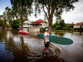 Roger Barnes rescues a friend's surfboard from a flooded home in the inner Brisbane suburb of Newmarket on January 28, 2013 as high winds and heavy rains brought by ex-tropical cyclone Oswald have hit the state of Queensland. Helicopters plucked dozens of stranded Australians to safety in dramatic rooftop rescues on January 28 as severe floods swept the northeast, killing three people and inundating thousands of homes. AFP PHOTO / Patrick HAMILTONPATRICK HAMILTON/AFP/Getty Images