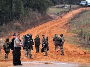 Law enforcement personnel work at check point Wednesday, Jan. 30, 2013, in Midland City, Ala., near the home where the Tuesday's school bus shooting suspect is barricaded in a bunker with a young child as hostage. Police, SWAT teams and negotiators were at a rural property where a man was believed to be holed up in a homemade bunker Wednesday after fatally shooting the driver of a school bus and fleeing with a 6-year-old child passenger, authorities said. (AP Photo/The Dothan Eagle, Jay Hare)