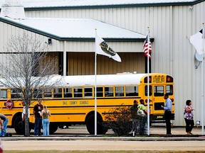 In this Tuesday, Jan 29, 2013 photo, residents look over the school bus where a shooting occurred near Destiny Church along U.S. 231, just north of Midland City, Ala. on Tuesday. Police, SWAT teams and negotiators were at a rural property where a man was believed to be holed up in a homemade bunker Wednesday, HAN 30, 2013 after fatally shooting the driver of a school bus and fleeing with a 6-year-old child passenger, authorities said. The man boarded the stopped school bus in the town of Midland City on Tuesday afternoon and shot the driver when he refused to let the child off the bus. The bus driver died. (AP Photo/The Dothan Eagle, Danny Tindell)