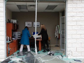 Two unidentified employees with the Your Neighbourhood Credit Union remove boxes from the scene of an accident, after a BMX X6 crashed through the front window. Thursday, January 3, 2013 in Windsor, Ont. The employee who normally works in that office was out for lunch when the accident occurred. The driver of the vehicle was transported to hospital for precautionary reasons. Windsor police are investigating. (JASON PRUPAS/ Special to the Star)