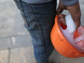 A man holds a hard hat in this file photo. (Dario Pignatelli/Bloomberg)
