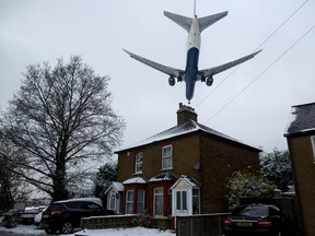 A plane flies over a residential area to land at Heathrow airport in west London on January 21, 2013 after the airport announced further flight cancellations due to adverse weather. London's Heathrow Airport warned of further flight cancellations on January 21 which would leave thousands more passengers stranded on the fourth day of delays after heavy snow swept across Britain. AFP PHOTO/ANDREW COWIE