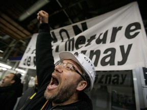 A striking worker demonstrates inside the French car manufacturer PSA Peugeot Citroen in Aulnay-sous-Bois, north of Paris, Monday, Jan. 28, 2013, as work was supposed to resume. The Aulnay plant has been at the center of a battle over the future of France's largest automaker. The company announced last year that it planned to cut 8,000 jobs and close Aulnay as it struggles to compete in Europe's stagnant car market. The banner reads: "No to the Closure of PSA Aulnay". (AP Photo/Christophe Ena)