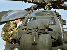 In this file picture taken on September 7, 2012 Britain's Prince Harry looks in the interior of an Apache helicopter with a member of his 622 Squadron, 3 Regiment Army Air Corps, part of 16 Air Assault Brigade, at Camp Bastion in Helmand Province, Afghanistan. (AFP PHOTO / POOL / JOHN STILLWELL)