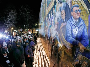 People gather in front of a mural containing a likeness of former Penn State football coach Joe Paterno, right, at a candlelight memorial on the first anniversary of his death, Tuesday, Jan. 22, 2013, in State College, Pa. (AP Photo/Gene J. Puskar)