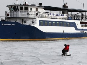 An unidentified ice fisher sits at his fishing hole through the ice in front of Macassa Bay at Lakeview Park Marina January 23, 2013. Temperatures have dipped recently, creating a new layer of ice on many inlets and ponds.  Dock fishermen nearby were being cautious of thin ice and abiding by the 'use at your own risk' warning.  (NICK BRANCACCIO/The Windsor Star)