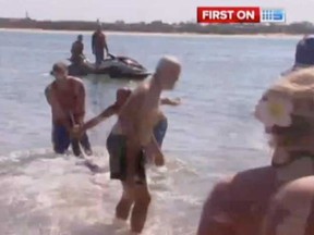 A British man wrestles a shark away from children frolicking at a beach in Australia. (Associated Press video grab)