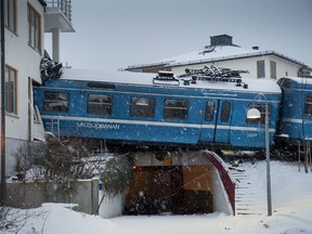 Derailed train that hangs on the edge of the track after it crashed into the side of a residential building in Saltsjobaden outside Stockholm, Tuesday Jan, 15, 2013. A woman obtained the keys to the train and drove it away before it crashed into the building. The woman was injured in the incident and there are no reports of injuries of people in the building . (AP Photo/Jonas Ekströmer)