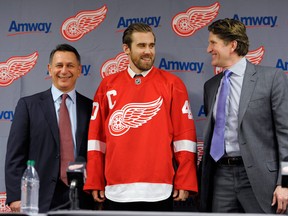 Detroit Red Wings general manager Ken Holland, left, and head coach Mike Babcock, right, stand with Henrik Zetterberg during an NHL hockey news conference announcing Zetterberg's appointment as team captain at Compuware Arena in Plymouth, Mich., Tuesday, Jan. 15, 2013. Zetterberg replaces retired defenseman Nicklas Lidstrom. (AP Photo/Detroit News, David Guralnick)