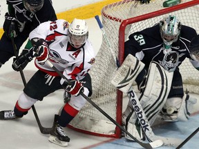 Windsor's Ben Johnson, centre, is checked by Plymouth's Colin MacDonald during a wraparound attempt against goaltender Alex Nedeljkovic. ( NICK BRANCACCIO/The Windsor Star)