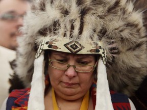 Attawapiskat Chief Theresa Spence, wearing a headdress, takes part in a drum ceremony before departing a Ottawa hotel to attend a ceremonial meeting at Rideau Hall with Gov. Gen. David Johnston in Ottawa, Friday January 11, 2013. THE CANADIAN PRESS/Fred Chartrand