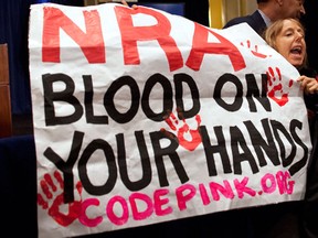 Activist Medea Benjamin, of Code Pink, is led away by security as she protests during a statement by National Rifle Association executive vice president Wayne LaPierre, left, during a news conference in response to the Connecticut school shooting on Friday, Dec. 21, 2012 in Washington. The National Rifle Association broke its silence Friday on last week's shooting rampage at a Connecticut elementary school that left 26 children and staff dead. (AP Photo/ Evan Vucci)