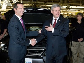 Ontario Premier Dalton McGuinty (left) and Prime Minister Stephen Harper shake hands after attaching the final parts to a Lexus SUV at the Toyota automotive plant in Cambridge, Ontario on Jan. 23, 2013. (THE CANADIAN PRESS/Frank Gunn)