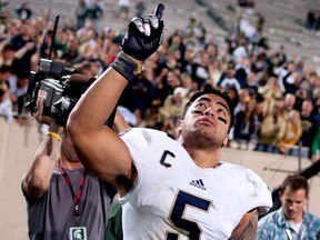 Notre Dame linebacker Manti Te'o points to the sky as he leaves the field after a 20-3 win against Michigan State in East Lansing, Mich. (AP Photo/South Bend Tribune, James Brosher)