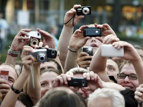 A group of people strain to capture a picture in this file photo. (SEBASTIAN WIDMANN/AFP/Getty Images)