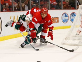 Detroit's Kyle Quincey tries to jump over Mikael Granlund of the Minnesota Wild to get to the puck at Joe Louis Arena on January 25, 2013 in Detroit, Michigan. Detroit won the game 5-3. (Gregory Shamus/Getty Images)