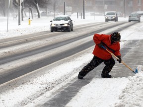 Windsor resident Peter Gerard takes on snow around a bus stop on Riverside Drive East near Solidarity Towers on Feb. 8, 2013. (Nick Brancaccio / The Windsor Star)