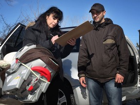 Gioia Levesque, left, and Talal Rafih, certified car inspectors with Safe Seats Save Children, inspect a child's car seat belonging to Sandra Maxwell, not pictured, who has a newborn baby, while at a free car seat clinic at Windsor Fire and Rescue station 7, Saturday, Feb. 9, 2013. (DAX MELMER/The Windsor Star)