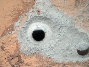 This image released by NASA on Saturday Feb. 9, 2013 shows a fresh drill hole, centre, made by the Curiosity rover on Friday, Feb. 8, 2013 next to an earlier test hole. Curiosity has completed its first drill into a Martian rock, a huge milestone since landing in an ancient crater in August 2012. (AP Photo/NASA)