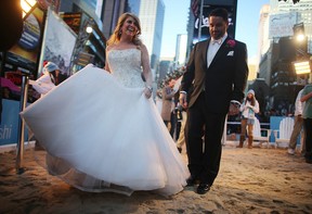 Brian Bondy (R) and new wife Melissa Cohn (L) walk on a mock beach in Times Square, New York City, after their whirlwind wedding on live U.S. television, Feb. 14, 2013. (Mario Tama / Getty Images)