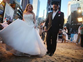 Brian Bondy (R) and new wife Melissa Cohn (L) walk on a mock beach in Times Square, New York City, after their whirlwind wedding on live U.S. television, Feb. 14, 2013. (Mario Tama / Getty Images)