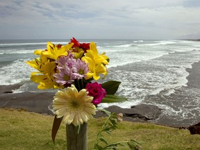 A flower tribute sits on a fence post as a memorial at Muriwai Beach near Auckland, New Zealand, Thursday, Feb. 28, 2013, a day after Adam Strange was killed by a shark. About 150 friends and family of Strange, 46, wrote messages to him in the sand and stepped into the water Thursday at a New Zealand beach to say goodbye after he was killed Wednesday by a large shark. (AP Photo/New Zealand Herald, Brett Phibbs)