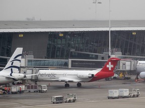 Baggage carts make their way past a Helvetic Airways aircraft from which millions' of dollars worth of diamonds were stolen on the tarmac of Brussels international airport, Tuesday, Feb. 19, 2013. Eight armed and masked men made a hole in a security fence at Brussels' international airport, drove onto the tarmac and snatched millions of dollars' worth of diamonds from the hold of a Swiss-bound plane without firing a shot, authorities said Tuesday. (AP Photo/Yves Logghe)