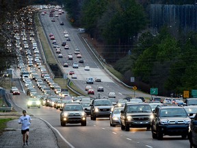 A jogger runs past backed-up traffic on U.S. 280 during afternoon rush hour in Mountain Brook, Ala., Monday, Feb. 4, 2013. (AP Photo/ AL.com, Mark Almond)