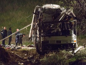 Investigators work at the scene, early Monday, Feb. 4, 2013, of the accident where at least eight people were killed and 38 people were injured Sunday after a tour bus carrying Mexican tourists careened out of control while traveling down a mountain road, striking a car, flipping and plowing into a pickup truck, near Yucaipa, Calif. (AP Photo/Ringo H.W. Chiu)