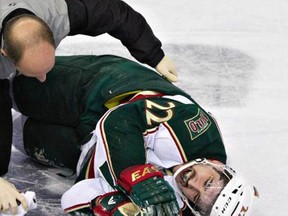 Minnesota Wild's Cal Clutterbuck is tended to by a trainer after being hit by Edmonton Oilers Taylor Hall. Photo: Jason Franson/THE CANADIAN PRESS