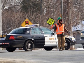 A flagman directs traffic while Ontario Provincial Police investigate the scene after a road worker was struck by a vehicle on County Road 22 near Puce Road in Lakeshore, Ontario on February 7, 2013. The worker was transported to hospital with unknown injuries. (JASON KRYK/The Windsor Star)