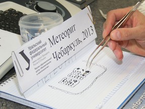 A handout photo taken on February 18, 2013, and provided by Urals Federal University shows pieces of porous black rock, reportedly fragments of the meteor that spectacularly plunged over Russia's Ural Mountains, as scientists work with them the universityâ€™s lab in Yekaterinburg. Scientists said today they had discovered fragments of the meteor that spectacularly plunged over Russia's Ural Mountains creating a shockwave that injured 1,200 people and damaged thousands of homes. AFP PHOTO / URAL FEDERAL UNIVERSITY/ ALEXANDER KHLOPOTOV