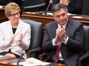 Ontario Premier Kathleen Wynne, left, and Finance Minister Charles Sousa applaud as Lieutenant Governor David Onley delivers the throne speech at the Ontario Legislature in Toronto on Tuesday, February 19, 2013, (THE CANADIAN PRESS/Chris Young)