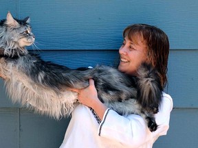 In this file photo taken July 1, 2009, Robin Henderson stretches out her Maine Coon cat Stewie outside of her home in Reno, Nev. The Reno owner of the longest domestic cat in the world says Stewie died Monday, Feb. 4, 2013 after a yearlong battle with cancer. Guinness World Records declared Stewie the record-holder in August 2010, measuring 48.5 inches from the tip of his nose to the tip of his tail. (AP Photo/Reno Gazette-Journal, Andy Barron)