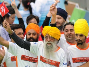 Indian-born British national Fauja Singh, centre,  waves a Hong Kong flag after crossing the finish line in the 10-km event as part of the Hong Kong Marathon on February 24, 2013. The 101-year-old Sikh believed to be the world's oldest marathon runner said on February 21 after arriving in the southern Chinese territory that he felt sad to be retiring from competitive events, as he prepared for his last race in Hong Kong.     (AFP PHOTO / Dale de la ReyDALE de la REY/AFP/Getty Images)