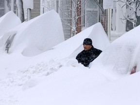 John Silver shovels snow between buried cars in front of his home on Third Street in South Boston, Saturday, Feb. 9, 2013. (AP Photo/Gene J. Puskar)