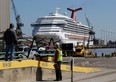 Workers look in the direction of the cruise ship Carnival Triumph in Mobile, Ala., Friday, Feb. 15, 2013. The ship, which Thursday docked in Mobile after drifting nearly powerless in the Gulf of Mexico for five days, was moved Friday from the cruise terminal to a repair facility. The ship carrying more than 4,200 passengers and crew members had been idled for nearly a week in the Gulf of Mexico following an engine room fire. (AP Photo/Dave Martin)