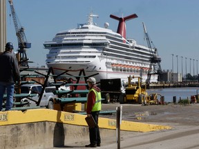 Workers look in the direction of the cruise ship Carnival Triumph in Mobile, Ala., Friday, Feb. 15, 2013. The ship, which Thursday docked in Mobile after drifting nearly powerless in the Gulf of Mexico for five days, was moved Friday from the cruise terminal to a repair facility. The ship carrying more than 4,200 passengers and crew members had been idled for nearly a week in the Gulf of Mexico following an engine room fire. (AP Photo/Dave Martin)