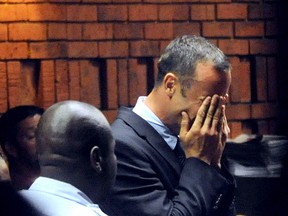 South Africa's Olympic sprinter Oscar Pistorius (R) hides his face in his hands in the court room during his hearing on charge of murdering his model girlfriend Reeva Steenkamp on Valentine's Day on February 15, 2013 at the Magistrate Court in Pretoria. South African prosecutors will argue that Pistorius is guilty of premeditated murder in Steenkamp's death, a charge which could carry a life sentence. AFP PHOTO/ Antoine de Ras