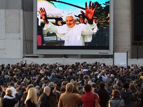 Faithful look at a giant screen on St Peter's square showing Pope Benedict XVI boarding a helicopter at the Vatican on February 28, 2013 at the Vatican. Pope Benedict XVI boarded a helicopter to fly to the papal summer residence of Castel Gandolfo outside Rome, where he will stay until his powers formally expire at 1900 GMT. AFP PHOTO / ALBERTO PIZZOLIALBERTO PIZZOLI