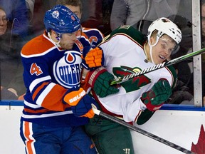 Ex-Spit Taylor Hall, left, hits Minnesota's Mikael Granlund of the Wild Thursday. (THE CANADIAN PRESS/Jason Franson)