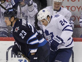 Winnipeg's Alexei Ponikarovsky, left, checks John-Michael Liles of the Maple Leafs at the MTS Centre in Winnipeg, (Photo by Marianne Helm/Getty Images)