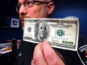 Sgt. Matt D'Asti of Windsor police holds an example of the counterfeit $100 USD bills that Toronto suspects have been circulating this week throughout the city. Photographed Feb. 28, 2013. (Nick Brancaccio / The Windsor Star)